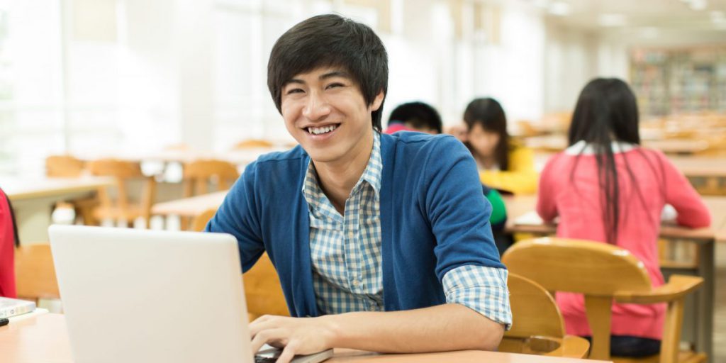 Student smiling while using laptop